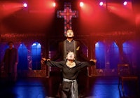 a man and woman standing on stage in front of a cross