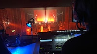 a man is sitting in front of a monitor in front of a stage