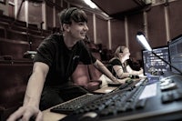 a man and a woman working on a computer in an auditorium